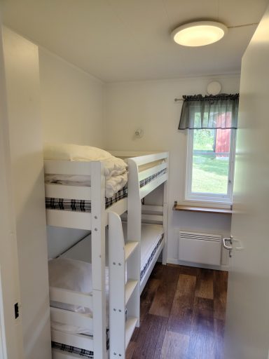 Ljust rum med våningssäng och fönster mot trädgården. 