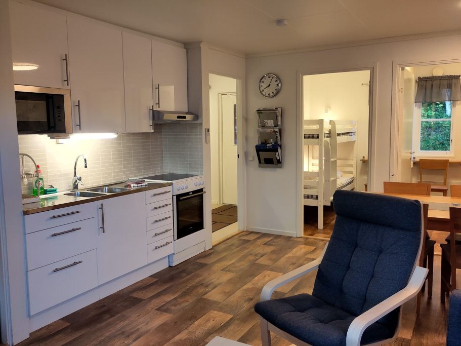 Allrum Moderna kök med matbord, bekväm stol och en våningssäng i angränsande rum.