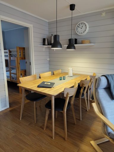 Möblerad matsal med ett träbord, stolar, väggur och ett mysigt hörn.