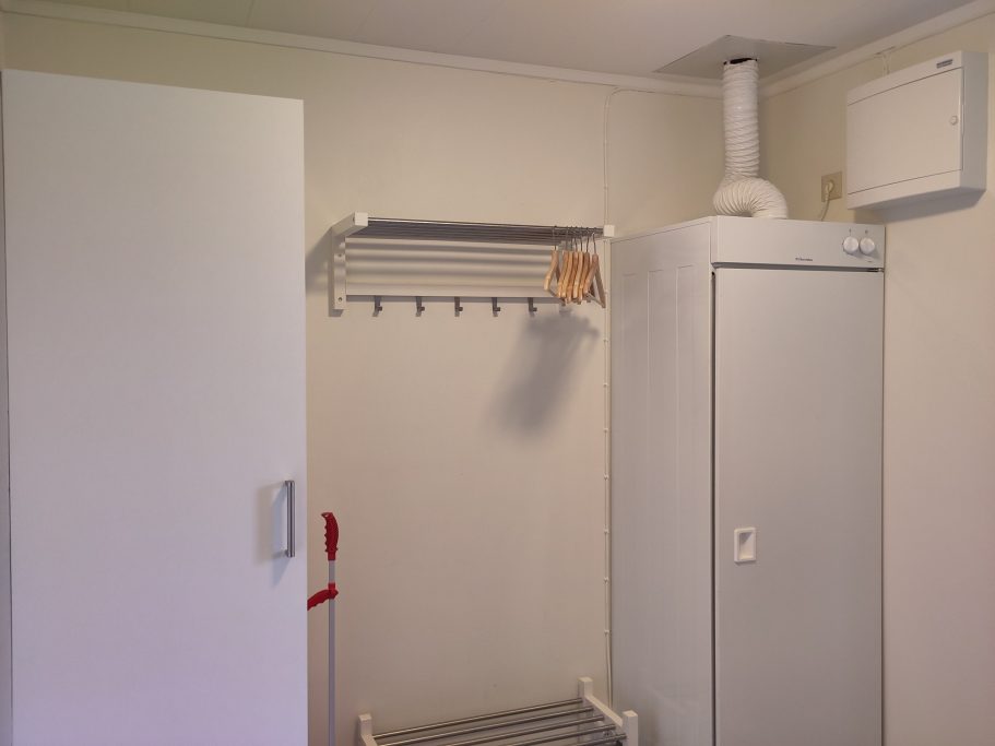 Hall Vitt skåp med hyllor och frys på en ljus vägg i ett rum.