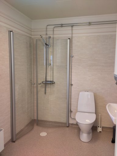 Badrum med dusch, toalett och handfat, ljusa väggar och modern inredning.