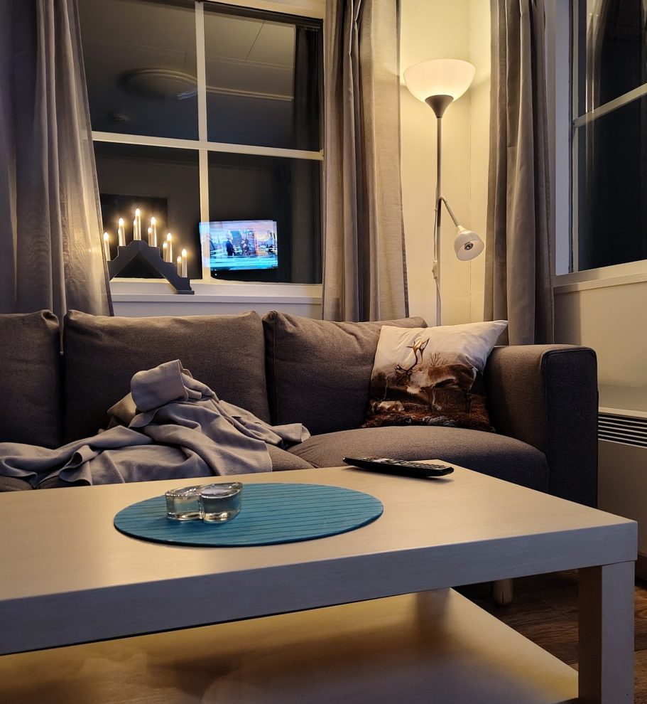 Mys Ett mysigt vardagsrum med soffa, bord, ljus och en tv i bakgrunden.