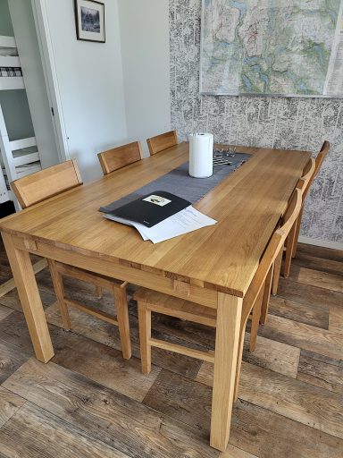 Ett träbord med stolar, en ljuslampa och en karta på väggen.