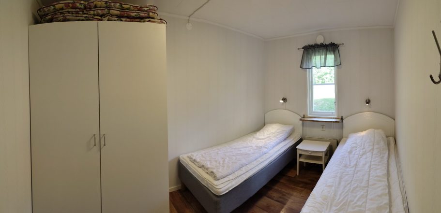Sovrum 1 Litet rum med två enkelsängar, garderob och fönster med utsikt.