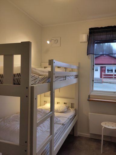 Sovrum med våningssäng och fönster mot gården. Varm och ljus inredning.