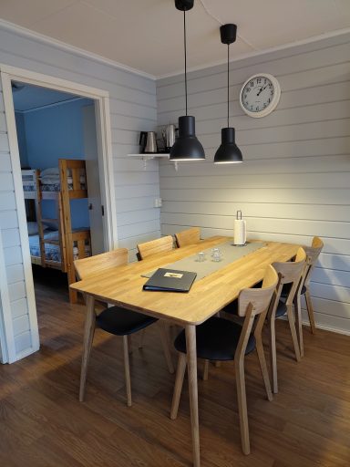 Ljusstark matplats med träbord, stolar och pendellampor i en ljus, modern miljö.