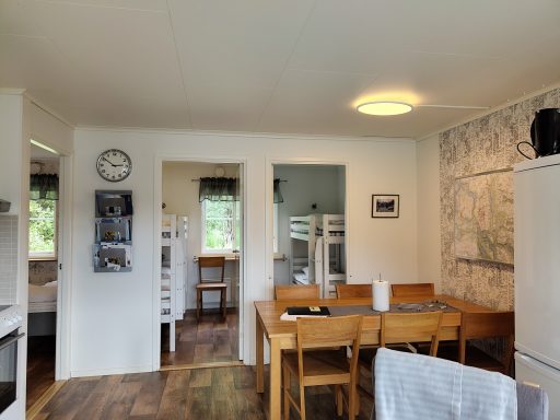 Ljus och öppen köksmiljö med matbord, stolar och moderna vitvaror.