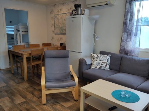 Modernt rum med soffa, fåtölj, matbord och kök. Ljust och luftigt.