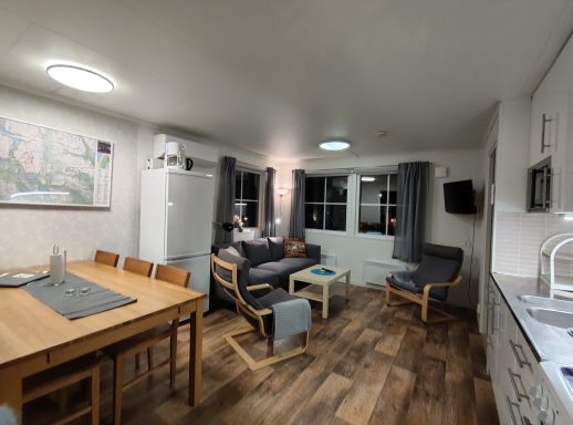 Modernt kök med matplats, soffa och ljusa fönster. Träinredning och vitvaror.