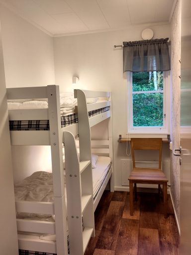 Sovrum med våningssäng, stol och fönster som släpper in naturligt ljus.