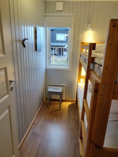 Litet rum med våningssäng, stol och fönster mot utsidan.