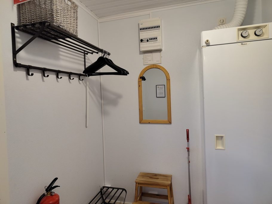 Hall Vitt rum med en spegel, klädhängare och förvaringshylla.