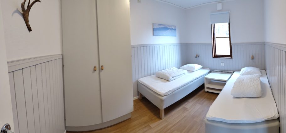 Sovrum 1 Ett ljust rum med två enkelsängar och en garderob.