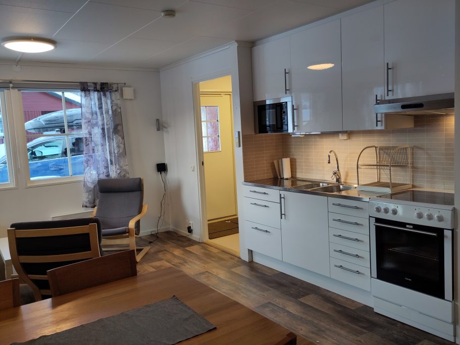 Kök Modernt kök med vit inredning, sittplats och fönster mot en uteplats.