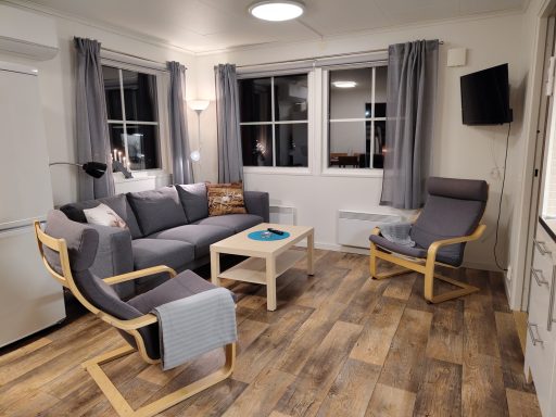 Vardagsrum med grå soffa, stolar, bord och fönster med utsikt.