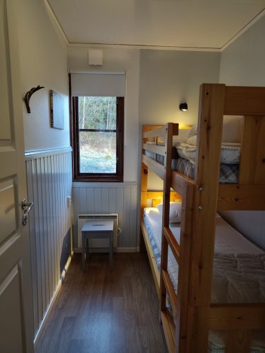 En liten rum med våningssängar och fönster som släpper in naturligt ljus.