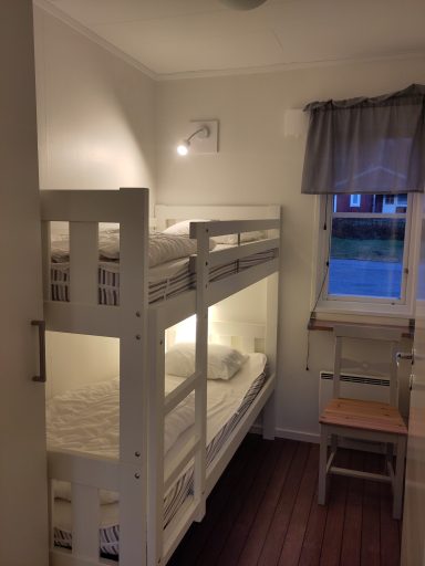 Sovrum med våningssäng och fönster, enkel inredning och ljus inredning.