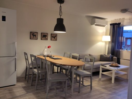 Kök med matbord, stolar, soffa och lampor i ett ljust rum.