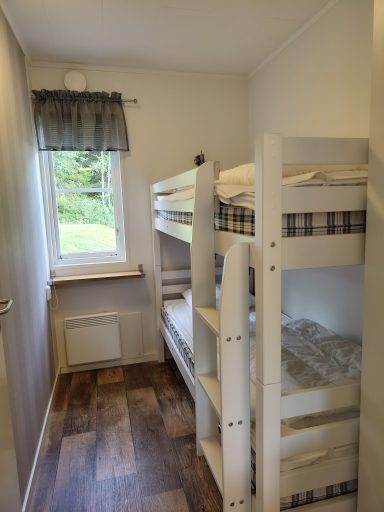 Kammare med våningssäng och fönster som vetter mot en grönskande utsikt.