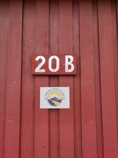 Röd vägg med nummer 20 B och en logotyp med en hand och en sol.