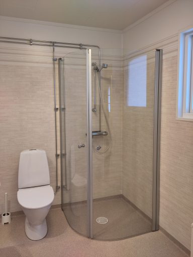 Badrum med dusch i glas och toalett i en neutral färgsättning.