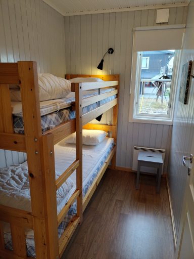 Sovrum med våningssäng och ett litet bord vid fönstret. Väggar i ljus färg.