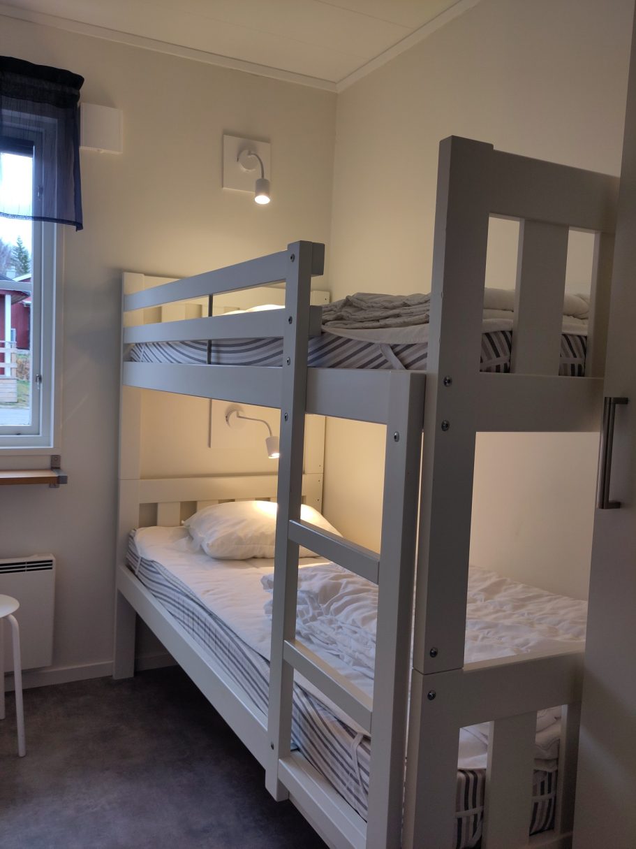 Sovrum3 Sovrum med våningssäng och en stol, ljusväggar och mjukt golv.