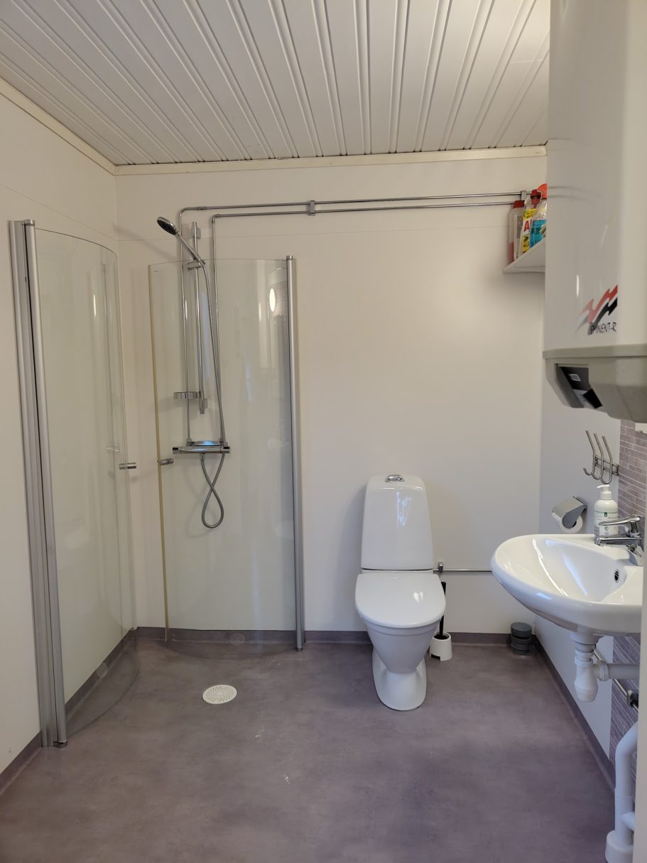 Badrum Badrum med dusch, toalett och handfat, ljusa väggar och golv.