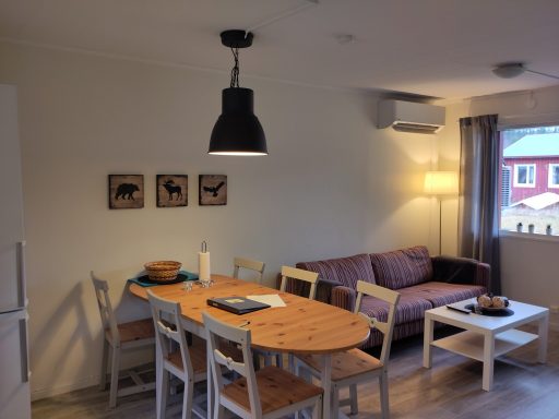 Ljust och luftigt vardagsrum med matbord, soffa och väggkonst.