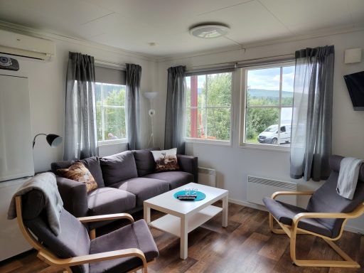 Ljust och luftigt vardagsrum med soffa, två fåtöljer och ett litet bord.