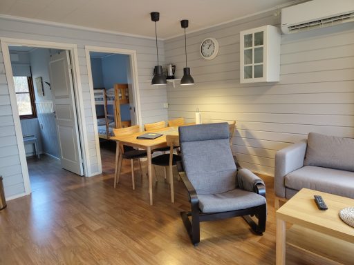 Vardagsrum med köksbord, stolar, fåtölj och soffa i ljusa färger.